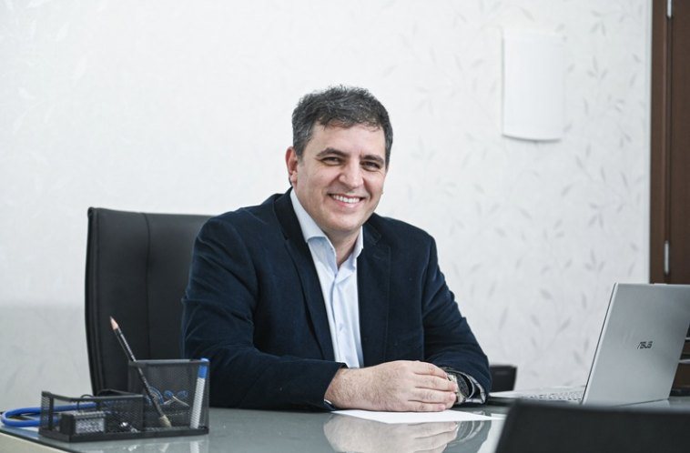 Dr. Vitor Augusto sorrindo à mesa do consultório